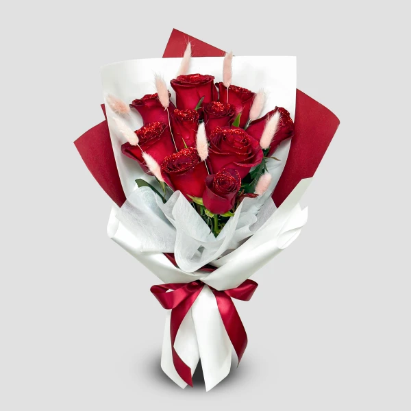 Bouquet of glittered red roses and bunny tails, wrapped in white and red paper with a red ribbon.