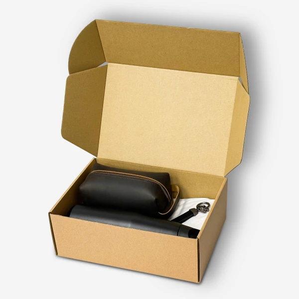 Brown cardboard box containing a black insulated tumbler, brown pouch, and black leather keychain.