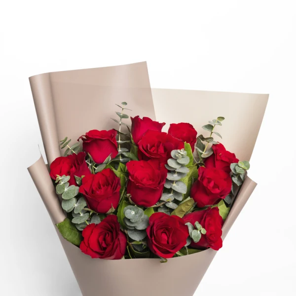 A bouquet of 12 red roses with eucalyptus in beige paper wrapping.