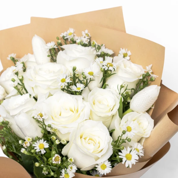 White roses and tulips with white asters, wrapped in brown paper.