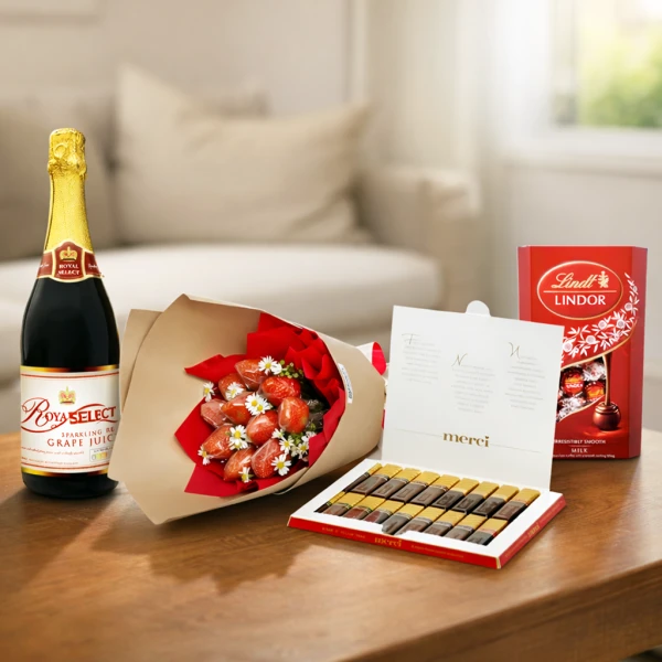 Champagne, strawberry bouquet, and chocolate boxes on a table.