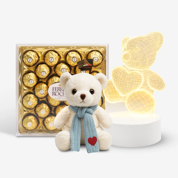White teddy bear with blue scarf and red heart, box of Ferrero Rocher chocolates, and a teddy bear light.