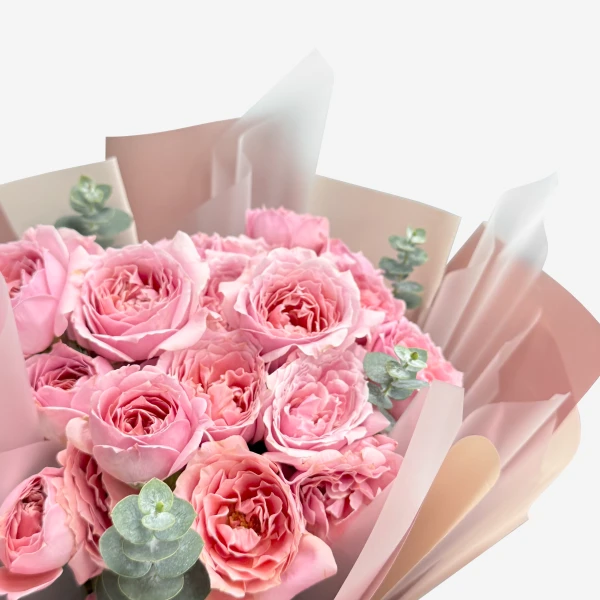 Bouquet of pink spray roses with eucalyptus, wrapped in soft pink paper.