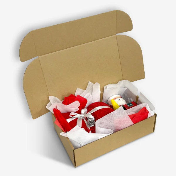 Open cardboard gift box filled with red and white tissue paper, a red ornament, and a Santa Claus figurine.