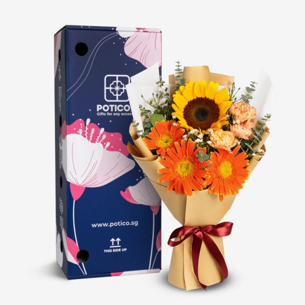 A bouquet of sunflowers, orange gerberas, and yellow carnations wrapped in brown paper with a burgundy ribbon.