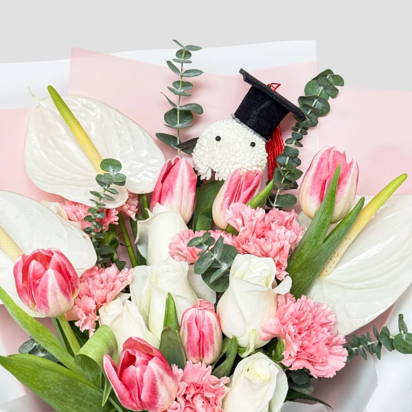 Bouquet with white anthuriums, pink and white tulips, pink carnations, and a graduation charm.