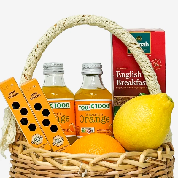 Wicker basket with orange juice, lemon, oranges, tea, and mini straws.