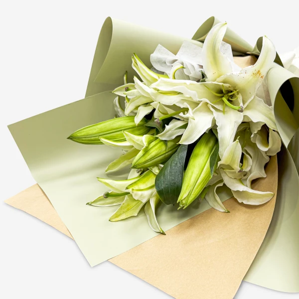 White lilies with green stems wrapped in light green and tan paper.
