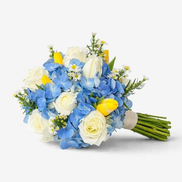 White roses, blue hydrangeas, yellow tulips, and small white flowers tied with a ribbon.
