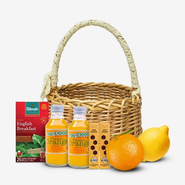 Wicker basket with orange juice, tea, mini straws, an orange, and a lemon.