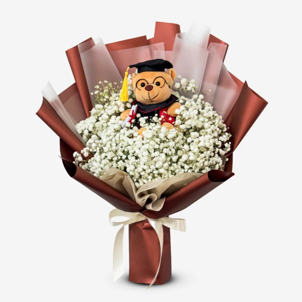 Graduation teddy bear in a bouquet of baby's breath with brown paper and ribbon.