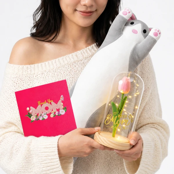 Woman holding a pink "Thank You Mom" card, a stuffed cat, and a glass dome with a lit tulip.