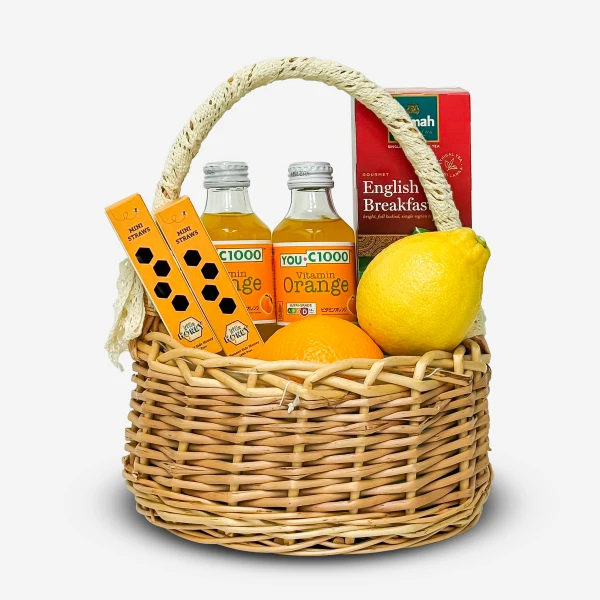Wicker basket with orange juice, lemon, oranges, tea, and mini straws.