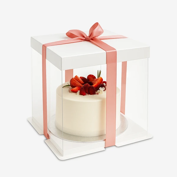 White cake with strawberries and raspberries in a clear box with a pink ribbon.