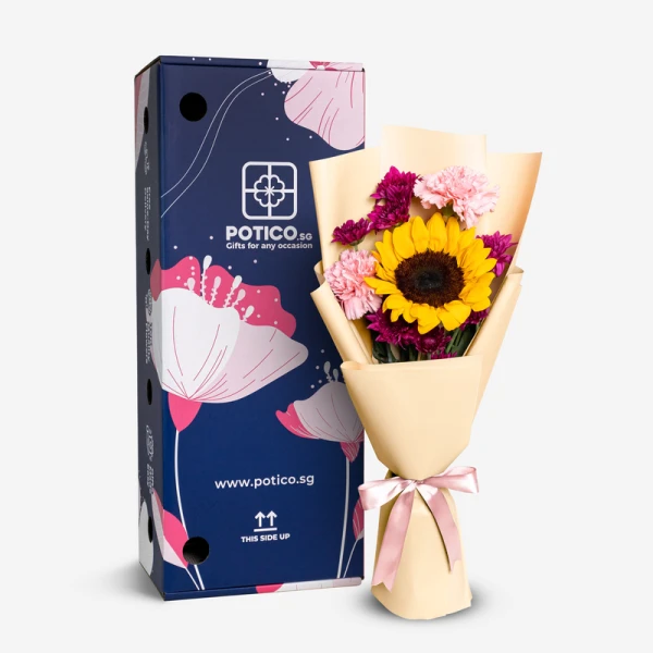 Sunflower, pink carnations, and purple chrysanthemums in a bouquet beside a navy blue gift box.