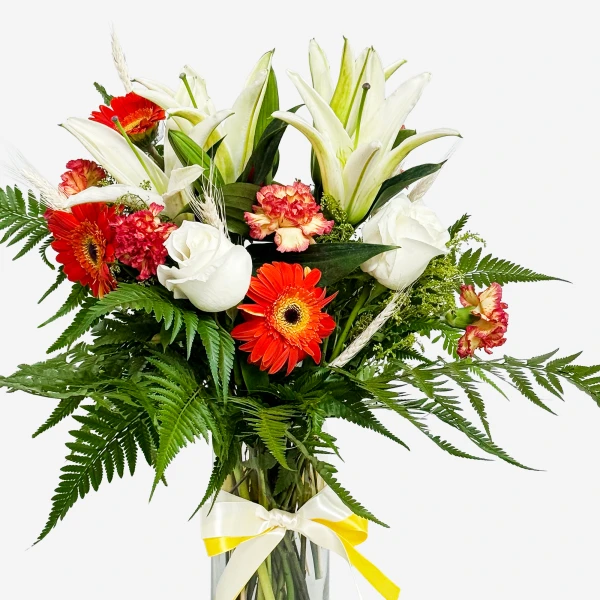 A vibrant bouquet of white lilies, orange gerbera daisies, red carnations, and white roses with green fern accents.