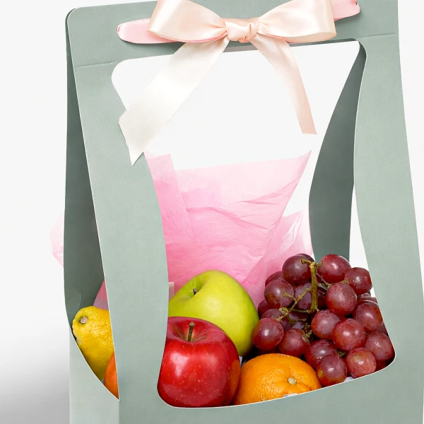 Gift basket with grapes, apples, orange, and lemon, tied with a pink bow.