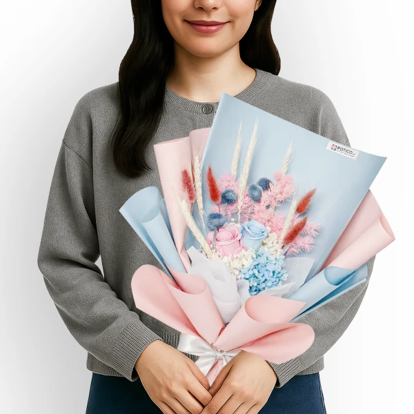 Woman holding a bouquet of pastel pink, blue, and white preserved flowers with dried accents.