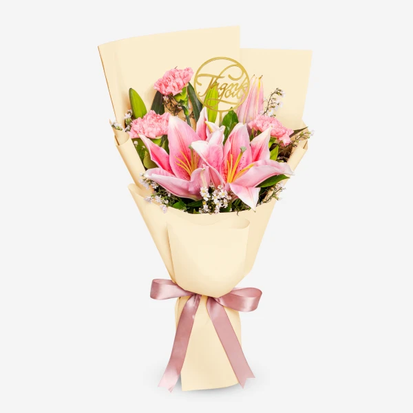 Pink lilies and carnations arranged in cream paper with a pink ribbon and "Thank You" topper.