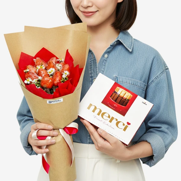 Person holding a strawberry bouquet and a box of Merci chocolates.