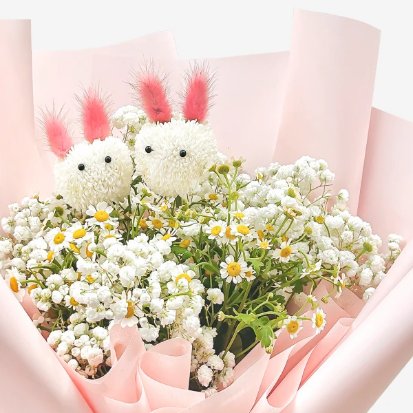 Cute floral bouquet with two bunny-shaped white mums, daisies, and baby's breath in pink paper.