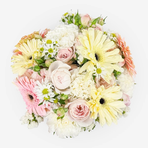 A round bouquet of soft pink and yellow gerbera daisies, roses, carnations, and small white daisies.