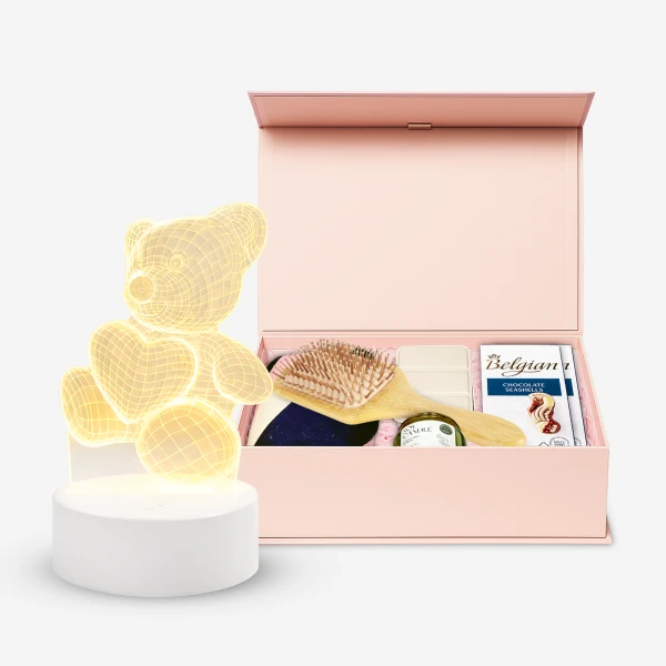 Pink gift box with teddy bear lamp and self-care items.