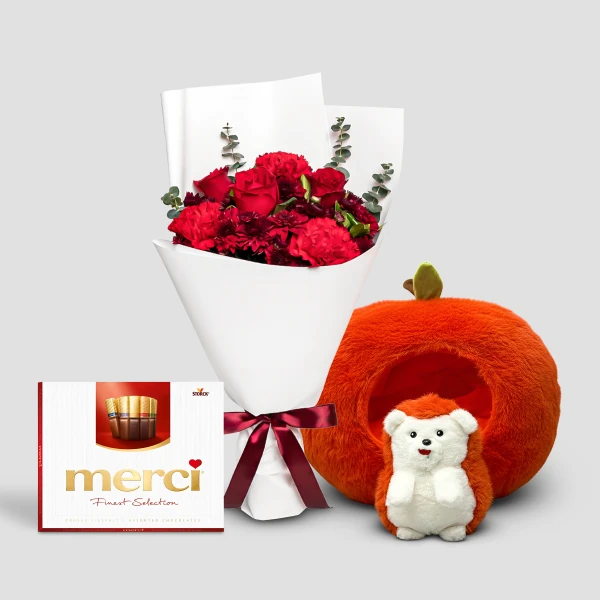 Red carnations and roses bouquet, Merci chocolates, and a plush hedgehog in an orange, pumpkin-shaped bed.