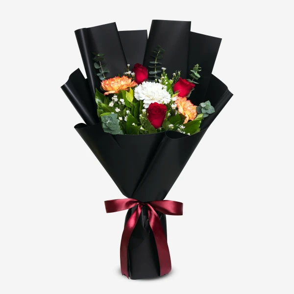 Bouquet of red roses, white and two-toned yellow carnations, and white phoenix flowers, wrapped in black paper and tied with a red ribbon.