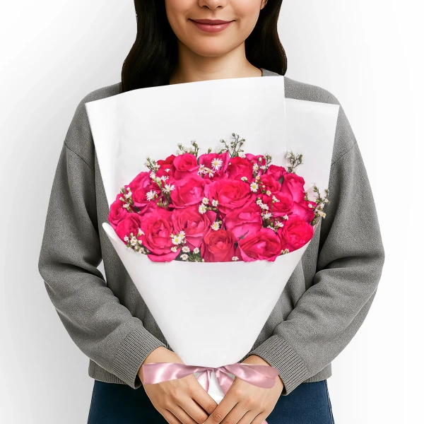 Woman holding a bouquet of 24 vibrant pink roses and white asters.