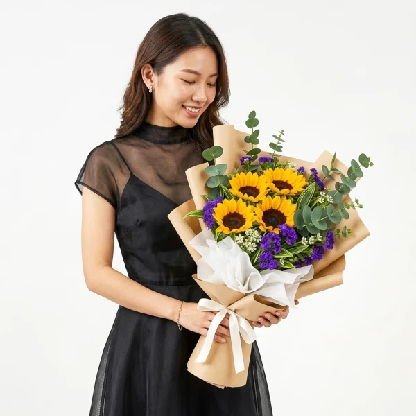 Graduating student holding a bouquet of sunflowers, purple statice, eucalyptus, and filler flowers wrapped in brown paper.