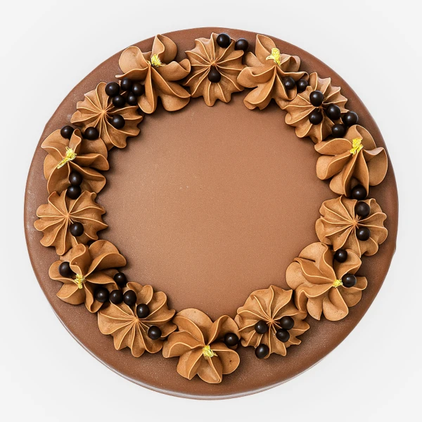 Chocolate cake decorated with piped chocolate frosting flowers and chocolate pearls around the edge.