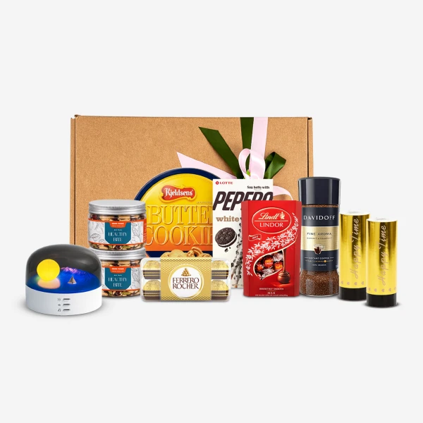 Gift basket with cookies, chocolates, coffee, and a diffuser with a glowing light.