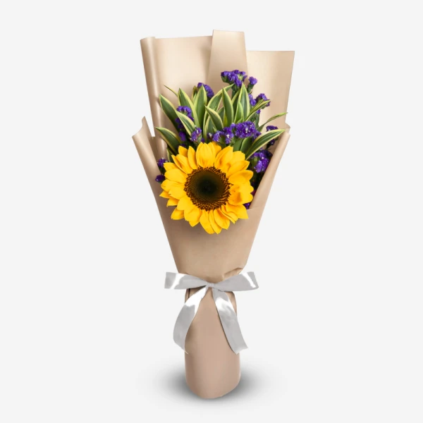 Sunflower with violet statice and green leaves in brown paper wrapping, tied with a white ribbon.