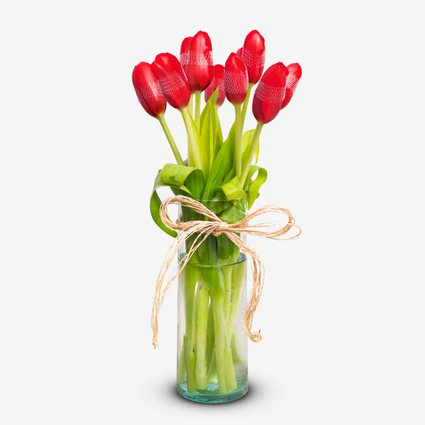 Red tulips in a glass vase with a twine bow.