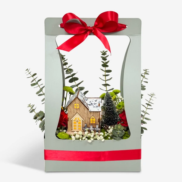 Festive miniature Christmas village scene inside a gift box with red ribbon.