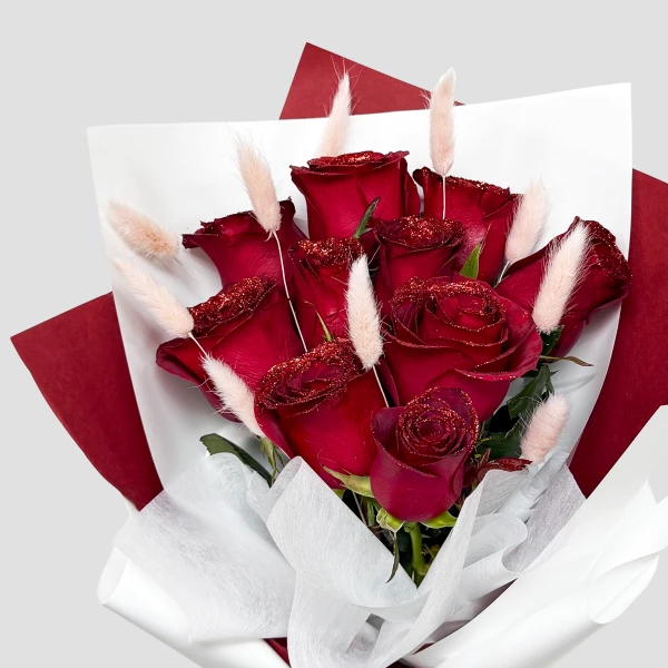 Glittered deep red roses and bunny tails arranged in a bouquet.