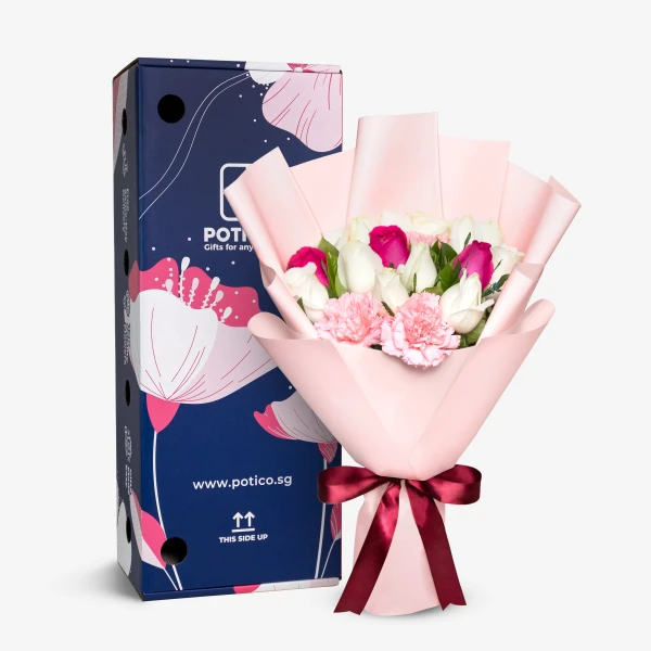 Bouquet of white and pink roses and pink carnations in light pink paper, tied with a burgundy ribbon, next to a blue box.