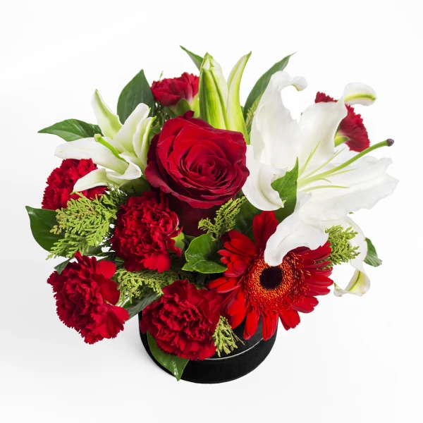 Round box of red and white flowers: red roses, carnations, gerberas, and lilies.