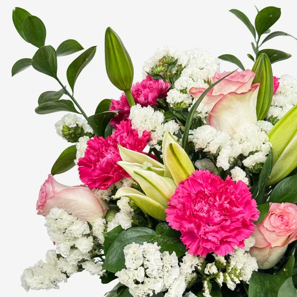 Close-up of a vibrant floral arrangement featuring pink carnations, lilies, roses, and white statice.