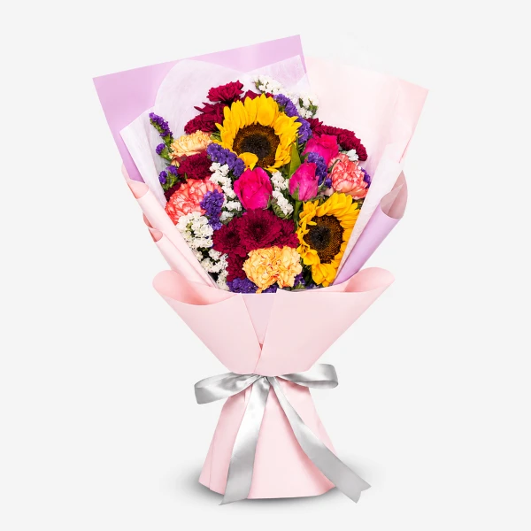 Vibrant bouquet with sunflowers, roses, carnations, and mums, wrapped in pink and purple paper with a silver ribbon.
