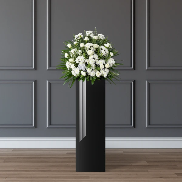 A white floral arrangement on a tall black stand.