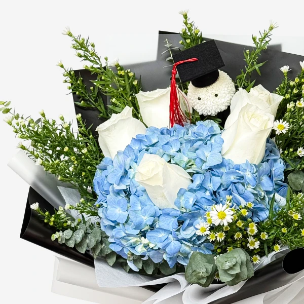 Blue hydrangea and white roses bouquet with graduation cap and teddy bear.