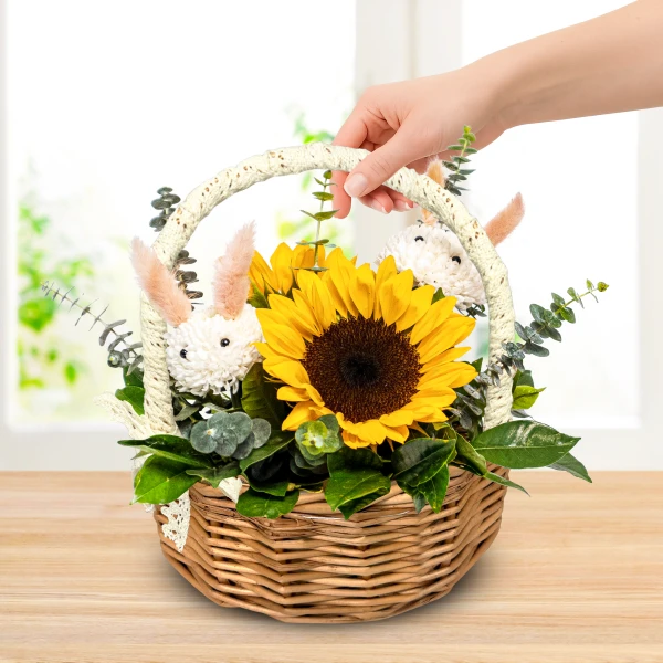 Sunflower bouquet with bunny decorations in a woven basket.