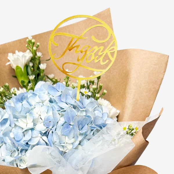 Bouquet of blue hydrangeas, white carnations, asters, and "Thank You" topper.