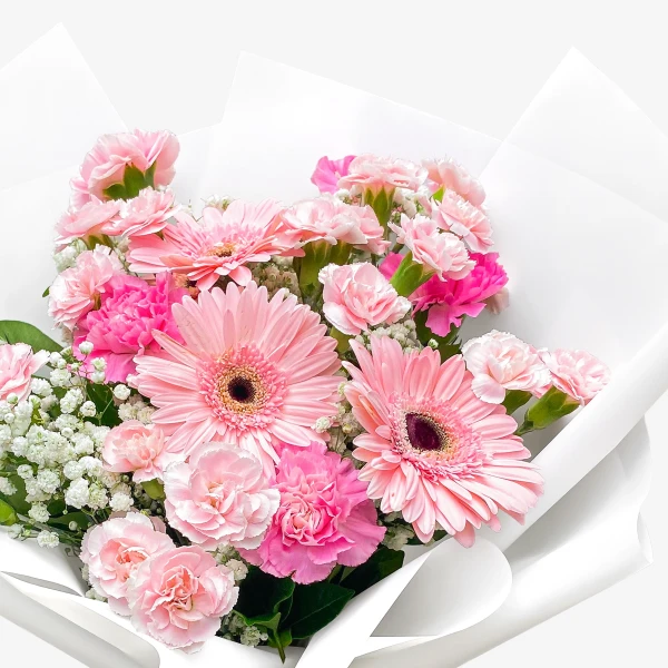 Pink gerberas and carnations in a bouquet with white paper wrap.