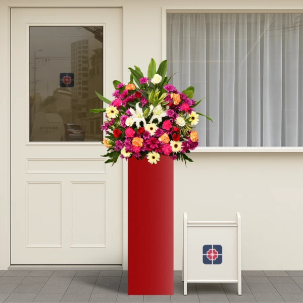 Red stand with colorful floral arrangement, white lilies, roses, carnations, gerberas, mums, cordyline and song of India.
