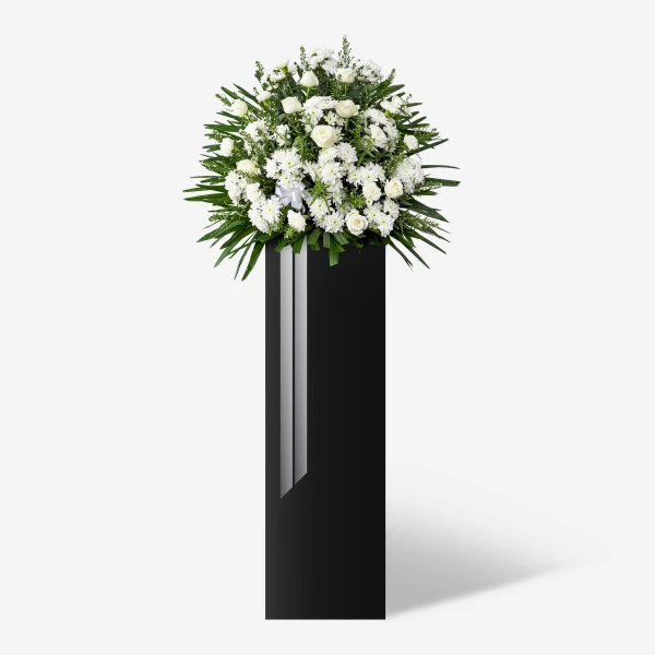 White roses, mums, and carnations overflow from a tall black stand, a symbol of peace for funeral tributes.