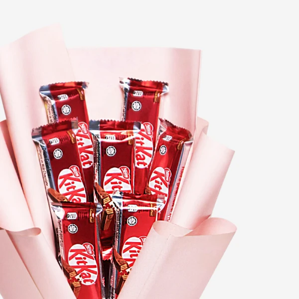 A bouquet of 7 red and silver KitKat chocolate bars wrapped in pink paper.