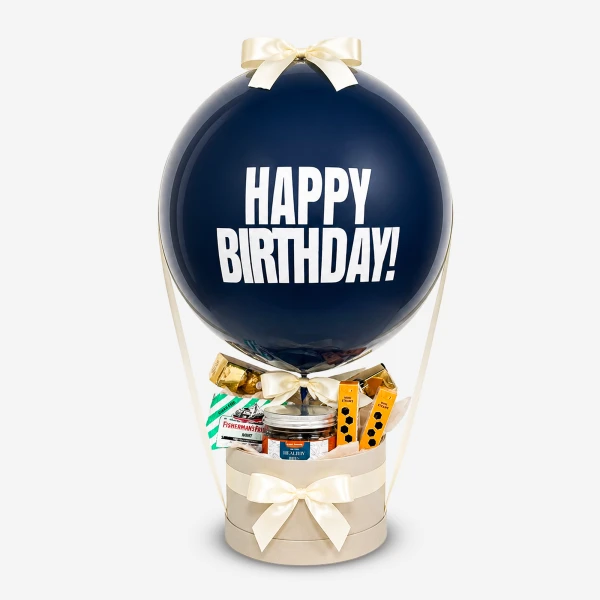 Navy blue balloon with "HAPPY BIRTHDAY!" text floating above a gift box filled with treats and tied with a bow.